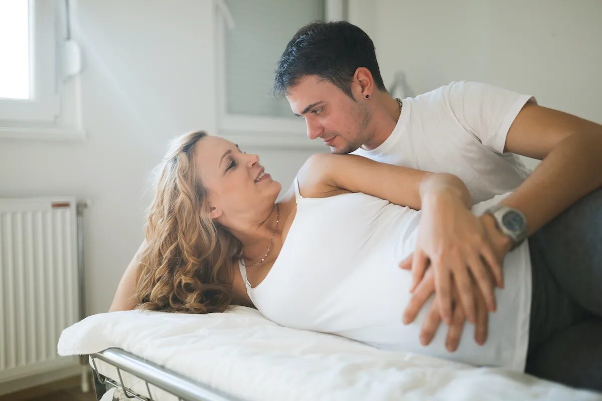Фотосессия беременной с мужем на кровати. Парень лежит с беременной женой. Чужая жена в постели