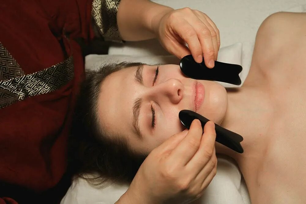 Массаж гуаша видео уроки. Массаж гуаша для лица. Китайский массаж лица гуаша техника. Массаж новокосинская мила. Китайский лимфодренажный массаж лица гуаша.