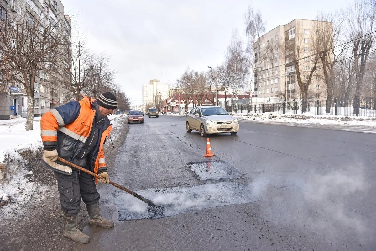 Дорожный рабочий. Ямочный ремонт. Розлив битума на тротуаре. Асфальт зимой.