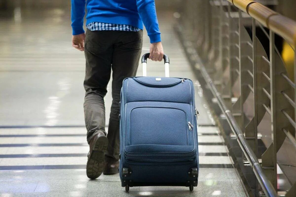 Уезжать ли за границу. Человек с чемоданом. Чемодан в аэропорту. Мужчина с чемоданом. Уезжает с чемоданом.