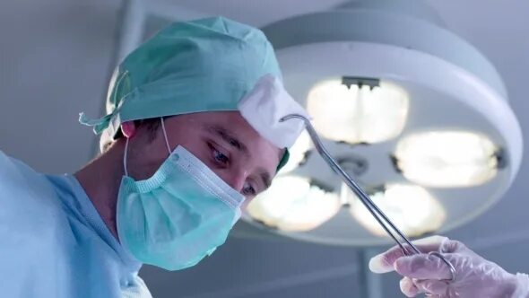 Одежда для оперирующих хирургов в операционной. Хирург во время операции: зажим. During the operation. During the operation. Хирургическая операция сестринское дело.