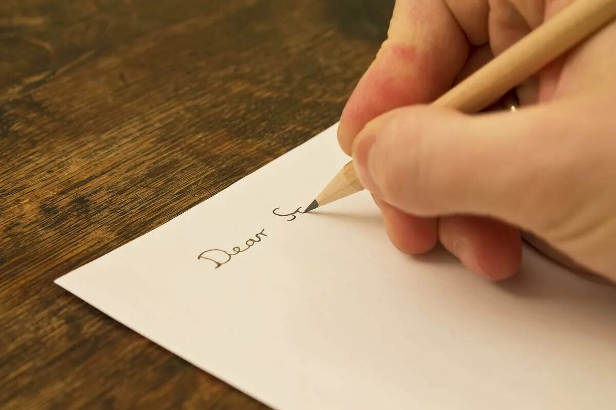Человек пишет на листе бумаги. Письмо. Пишет на бумаге. Листок бумаги. Человек пишет на бумаге.