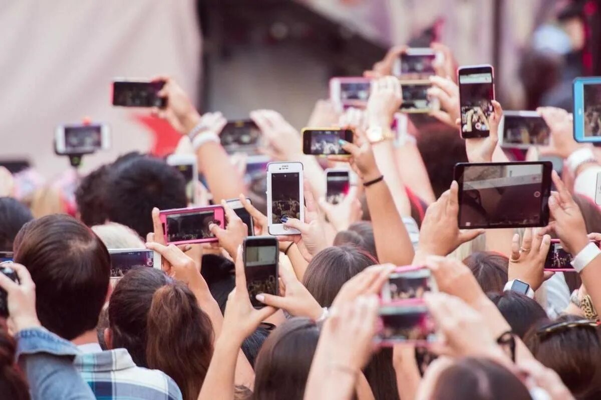 Много людей с мобильниками. Человек фотографирует на телефон. Толпа людей с гаджетами. Много людей с айфонами.