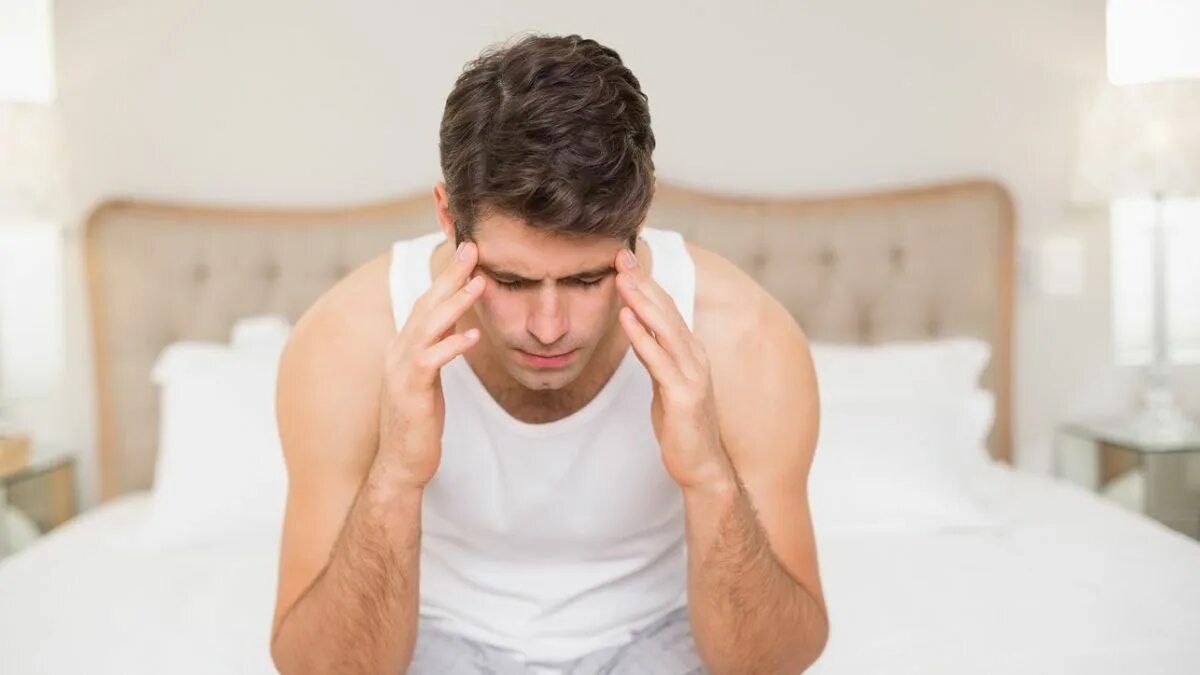 В постели с головной болью. Голова болит постель. Пациент в постели с головной болью. Стоковое фото у мужчины болит голова.