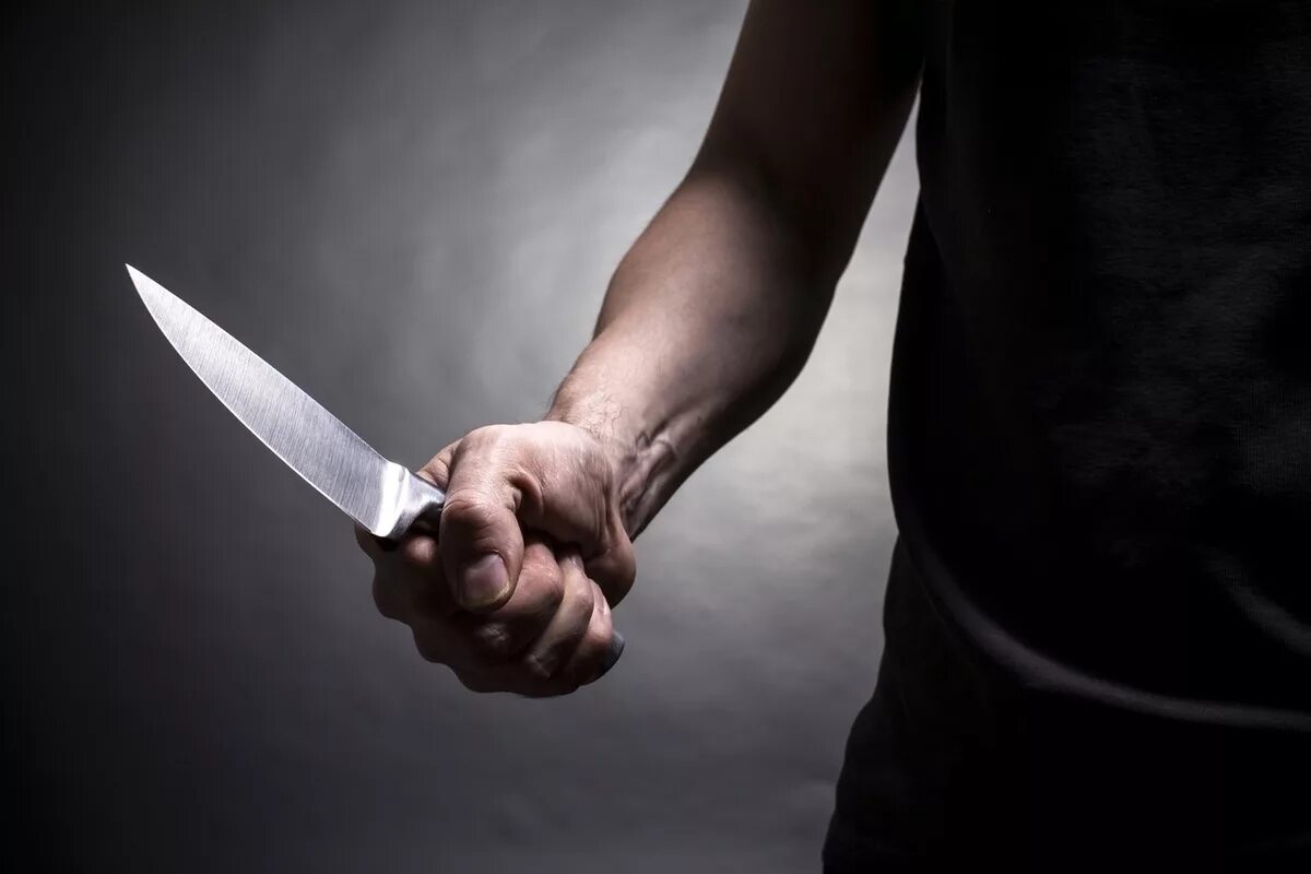 Человек угрожал ножом. Мужчинская рука с ножом.