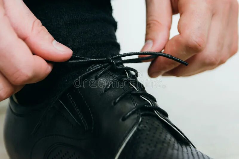 Связанные шнурки на ботинках. Шнурки на черной обуви. Шнурки для черных ботинок. Человек шнурует обувь. Завязал шнурки песня