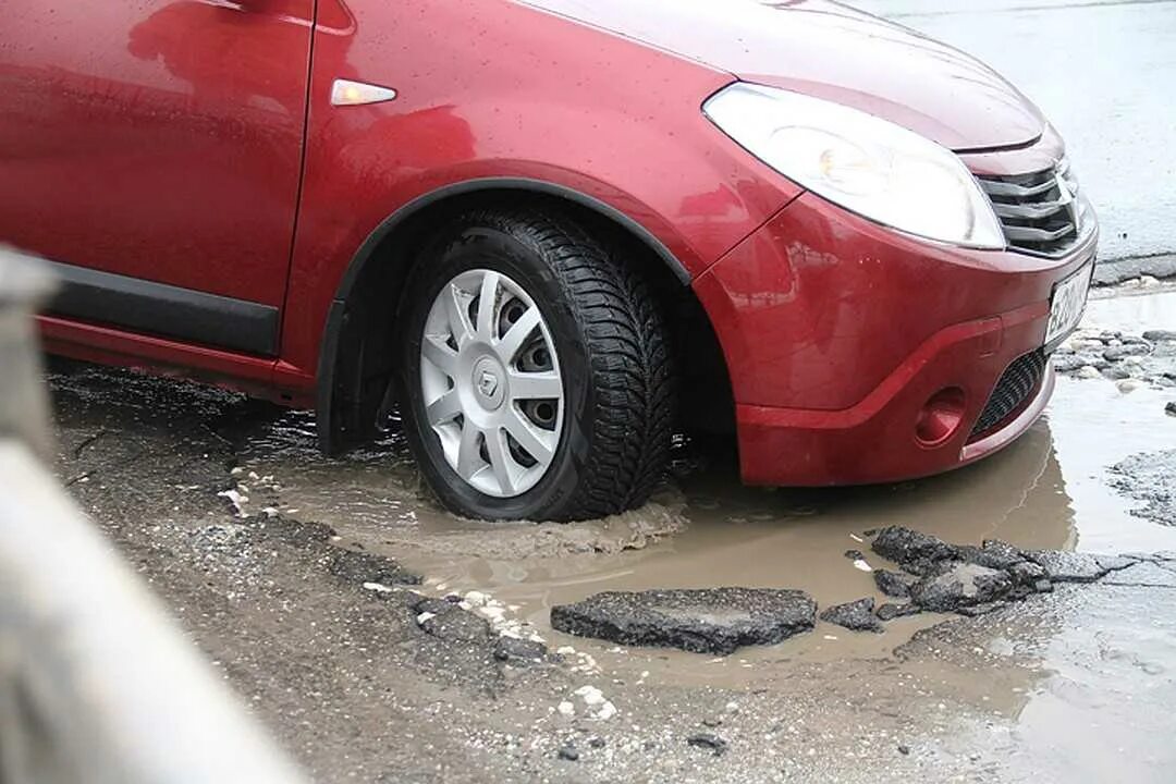 Колесо попало в яму на дороге. Колесо в яме. Колесо в яме на дороге. Пробитое колесо.