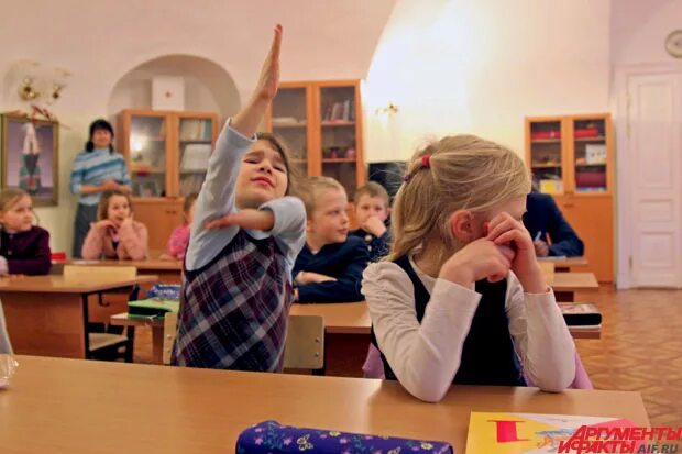 Школьники тянут руку на уроке. Школьник за партой тянет руку. Школьник поднимает руку. Дети в классе поднимают руки.