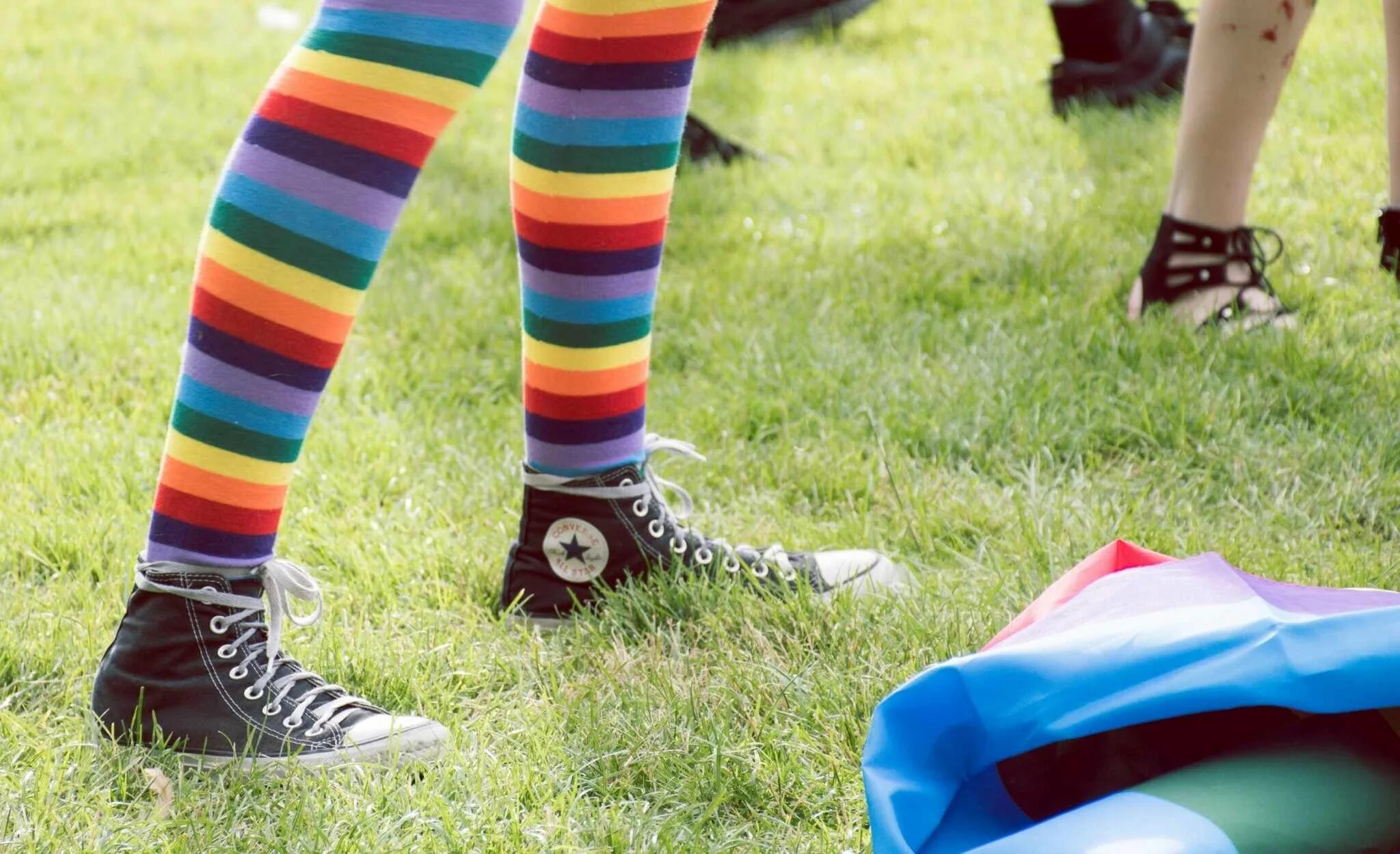 Ноги в радужных носках. Детские ноги в носках на траве. Волосатые ноги в радужных носках. Яркие ботинки на траве. Wearing socks