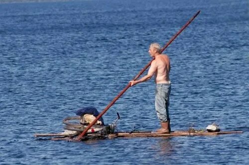 Путешественник переплыл спокойное озеро на яхте. Человек плывет на бревне. Люди на плату. Человек на плоту. Мужик на лодке.