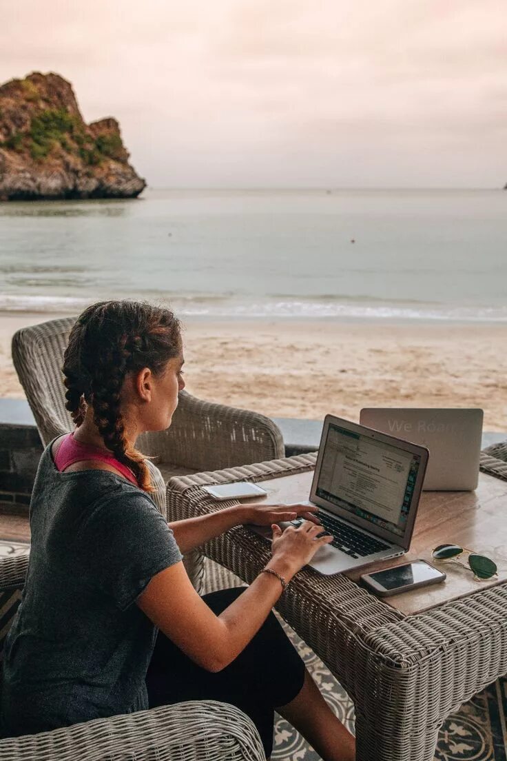Удаленная работа. Девушка путешествует с ноутбуком. Девушка с ноутбуком на море. Девушка с ноутбуком на берегу моря.