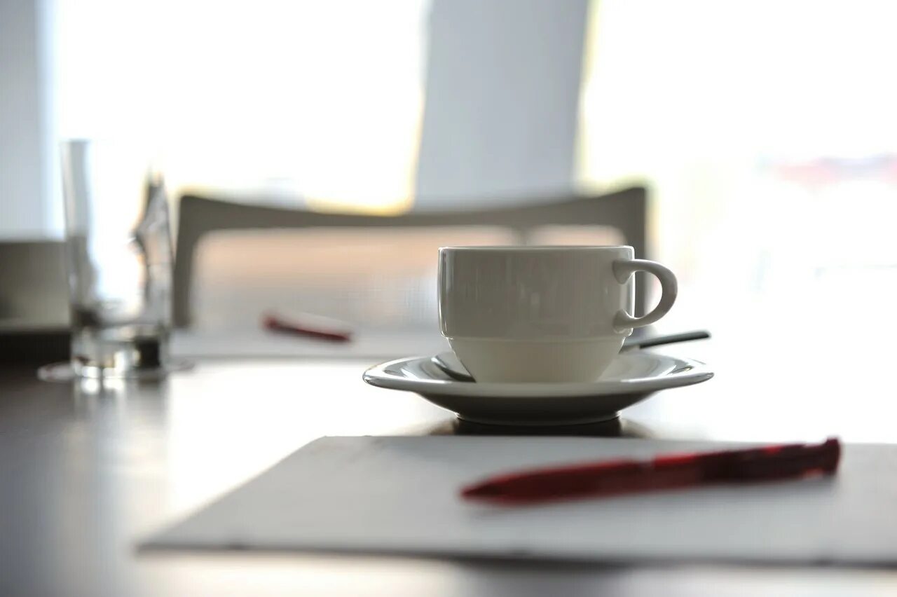 There is a cup on the table. Комната чашка на столе. Кружка кофе на столе следователя. Кофе в офисе на рабочем столе фото. Картинка на рабочий стол для офиса с чашкой.