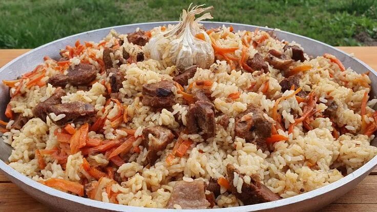 The concept of oriental cuisine. Homemade Uzbek pilaf from lamb served in cast i