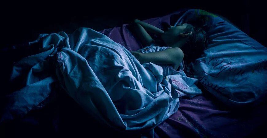 Сон в темноте. Девушка в кровати ночью.