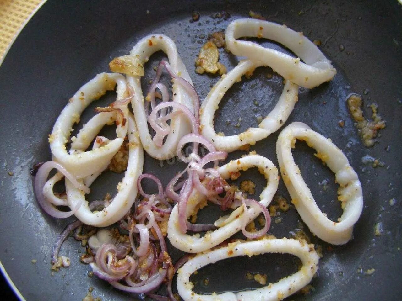 Кальмар рецепт на сковороде простой. Кальмар на сковороде. Жареные кольца кальмара на сковороде. Кальмар жареный с луком. Жареные кальмары на сковороде с луком.