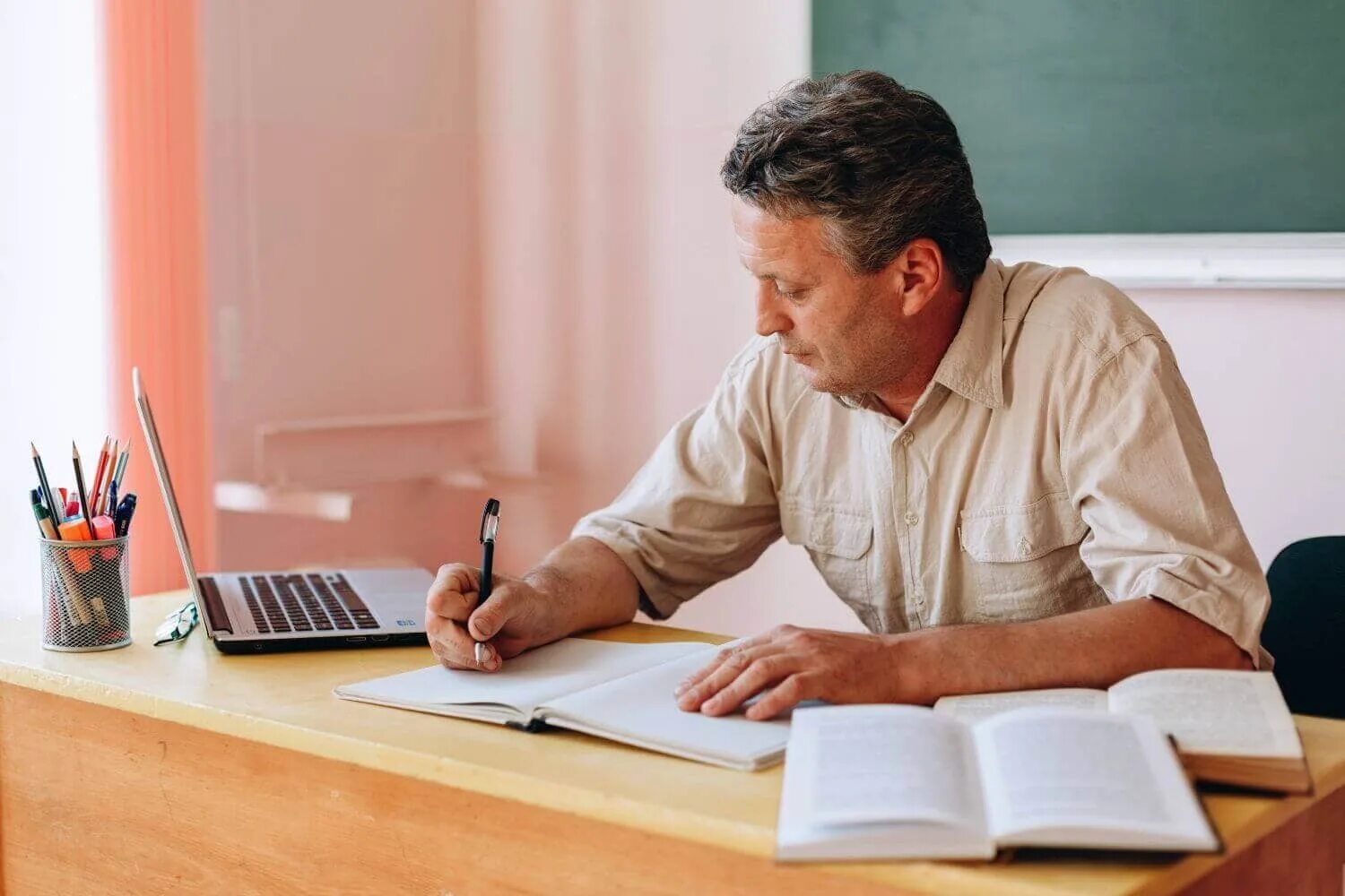 Taller teacher. Преподаватель сидит за столом. Учитель сидит за столом. Мужчина учитель за столом. Увител чидит за столом.