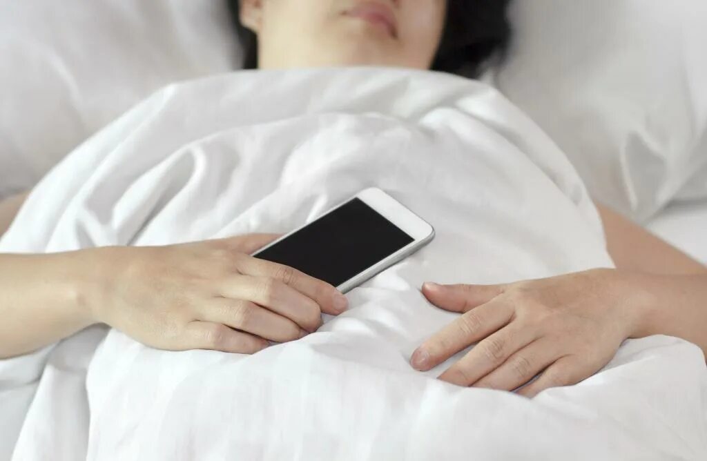 Спать в телефоне играть. В постели с телефоном. Человек с телефоном в руках в кровати. Человек в кровати со смартфоном. Смартфон лежит.