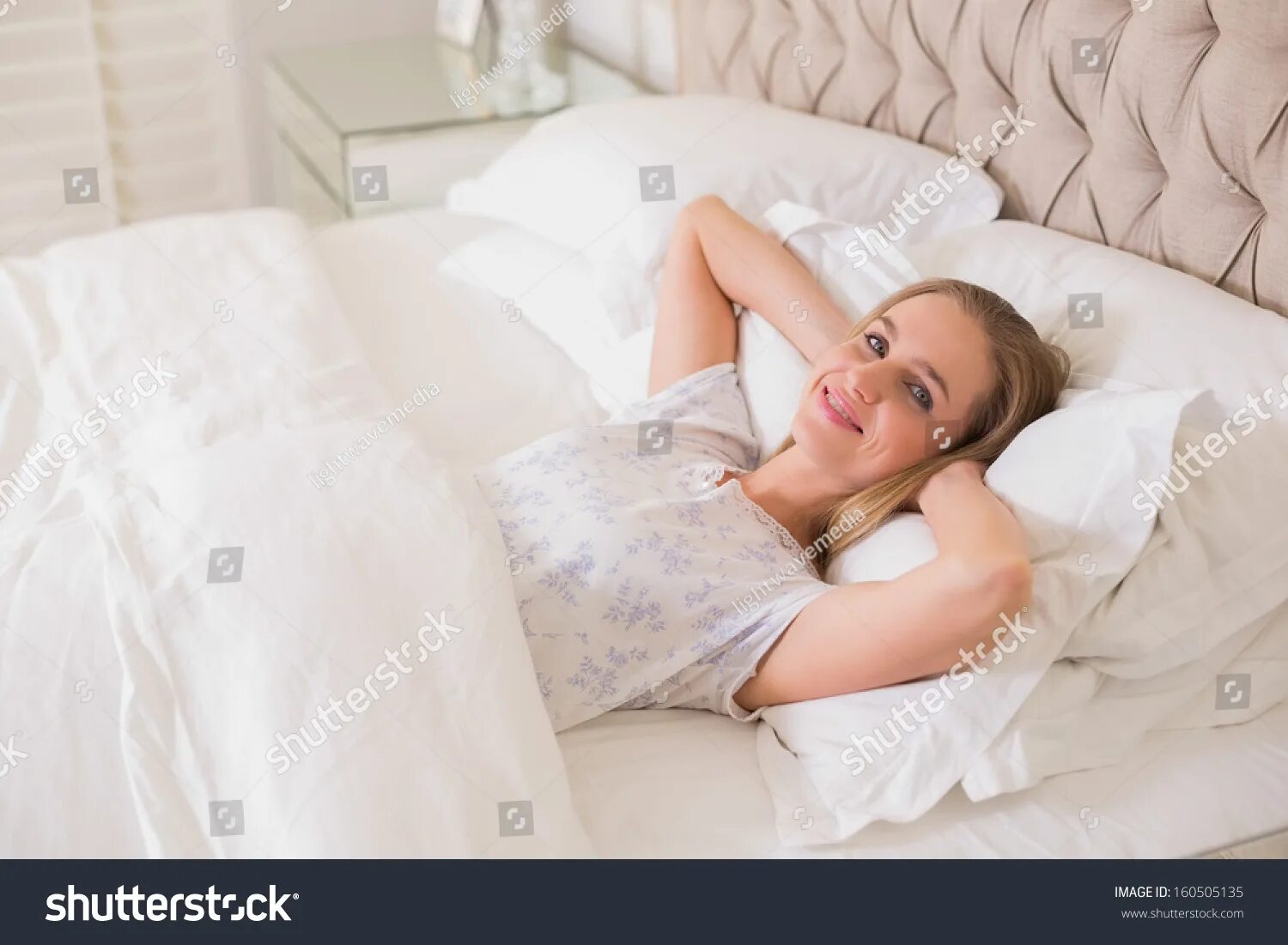 Белокурая женщина отдыхает на кровати. Невеста прилегла отдохнуть на кровать. Отдыхать в постели