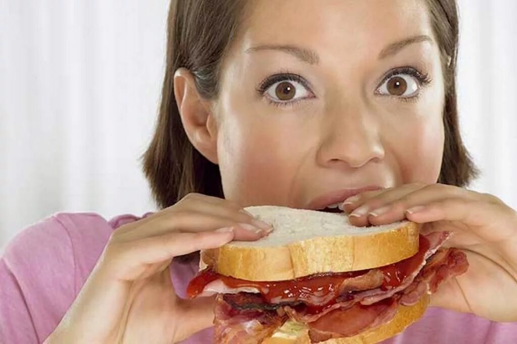 Появился сильный аппетит. Девушка с бутербродом. Переедание. Человек ест бутерброд. Женщина переела.