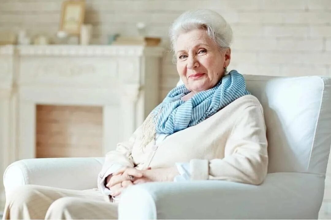 В скромно обставленном кабинете сидел пожилой человек. Пожилая женщина сидит. Пожилая женщина в кресле. Бабушка в кресле. Пожилая женщина в красивом платье.