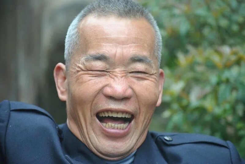 Китаец смеется. Китаец улыбается. Японцы смеются.