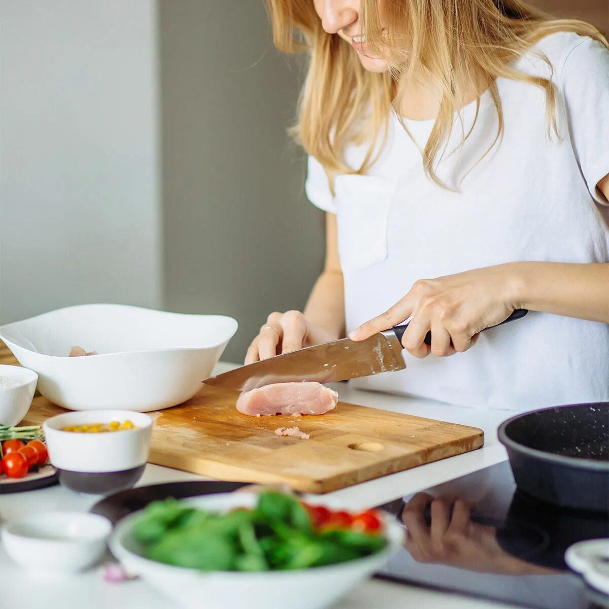 Девушка режет на кухне. Девушка с острыми ножами на кухне. Повар женщина режет мясо.