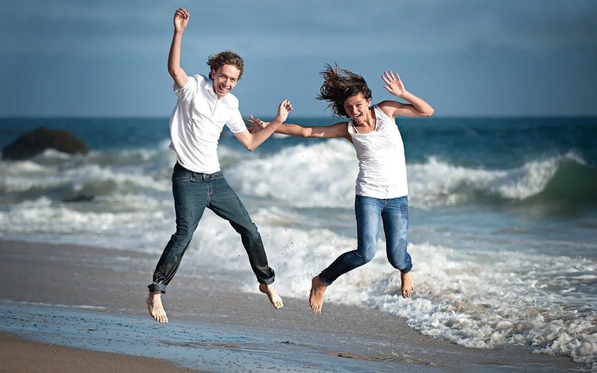 Веселая пара. Счастливая пара. Влюбленные бегут. Парень и девушка веселятся. Радостные люди на море.