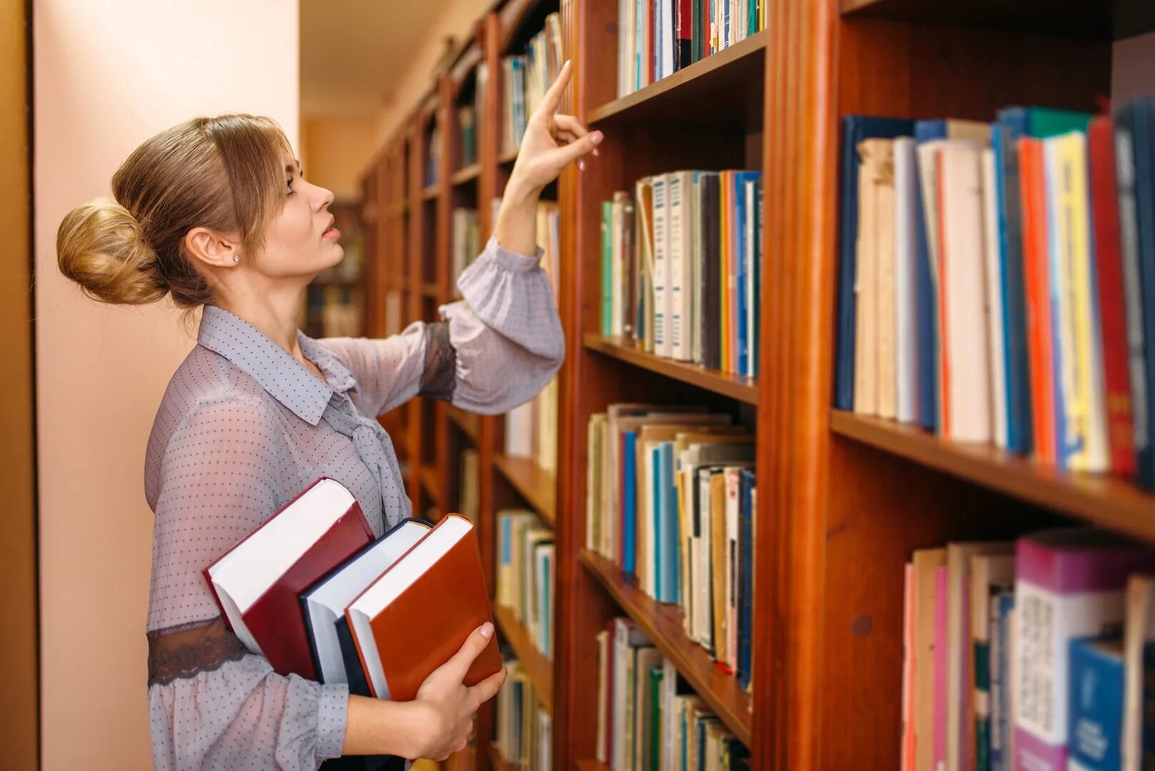 А можно книгу взять. Девушка в библиотеке. Фотосессия в библиотеке. В библиотеке библиотекарша.