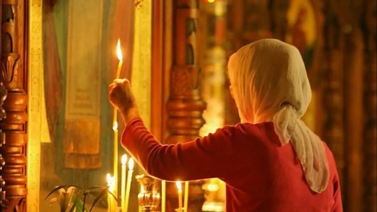 Человек молится в храме. Свеча у иконы в храме. Свечи перед иконой в храме. Человек перед иконой. Женщина прикладывается к иконе.