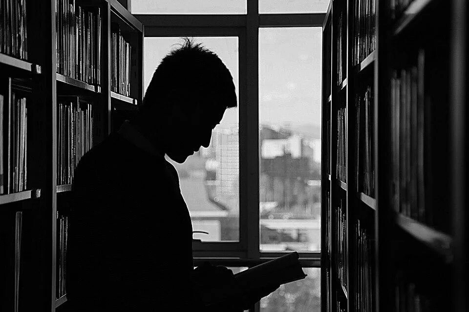 Книга человек. Парень с книгой. Мужчина в библиотеке. Чтение в темноте. Мужик читает стих