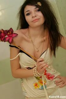 Cute girl Kaira 18 holds a stalk of flowers while posing clothed in a bathr...