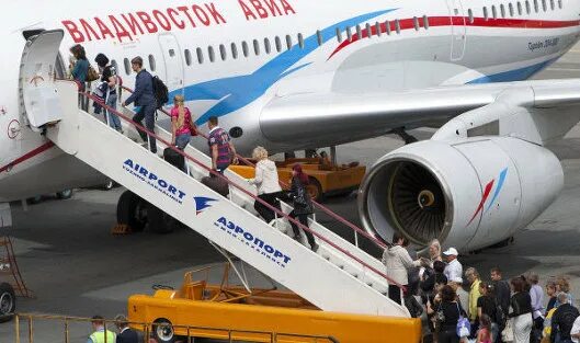 Владивосток авиа. Авиакомпания Владивосток. Люди заходят в самолет. Пассажиры заходят по трапу в самолет.