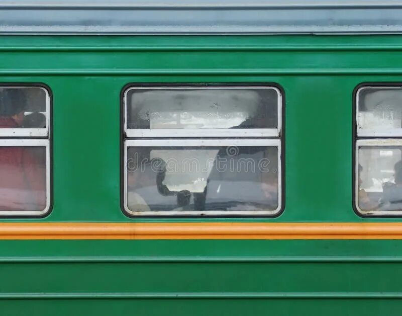 Пассажир стоит у окна в пассажирском поезде
