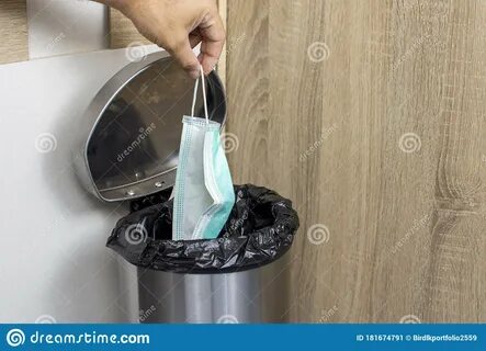 Disposable Medical Masks in a Hand Let Down To Infectious Waste Trash Bin. Stock