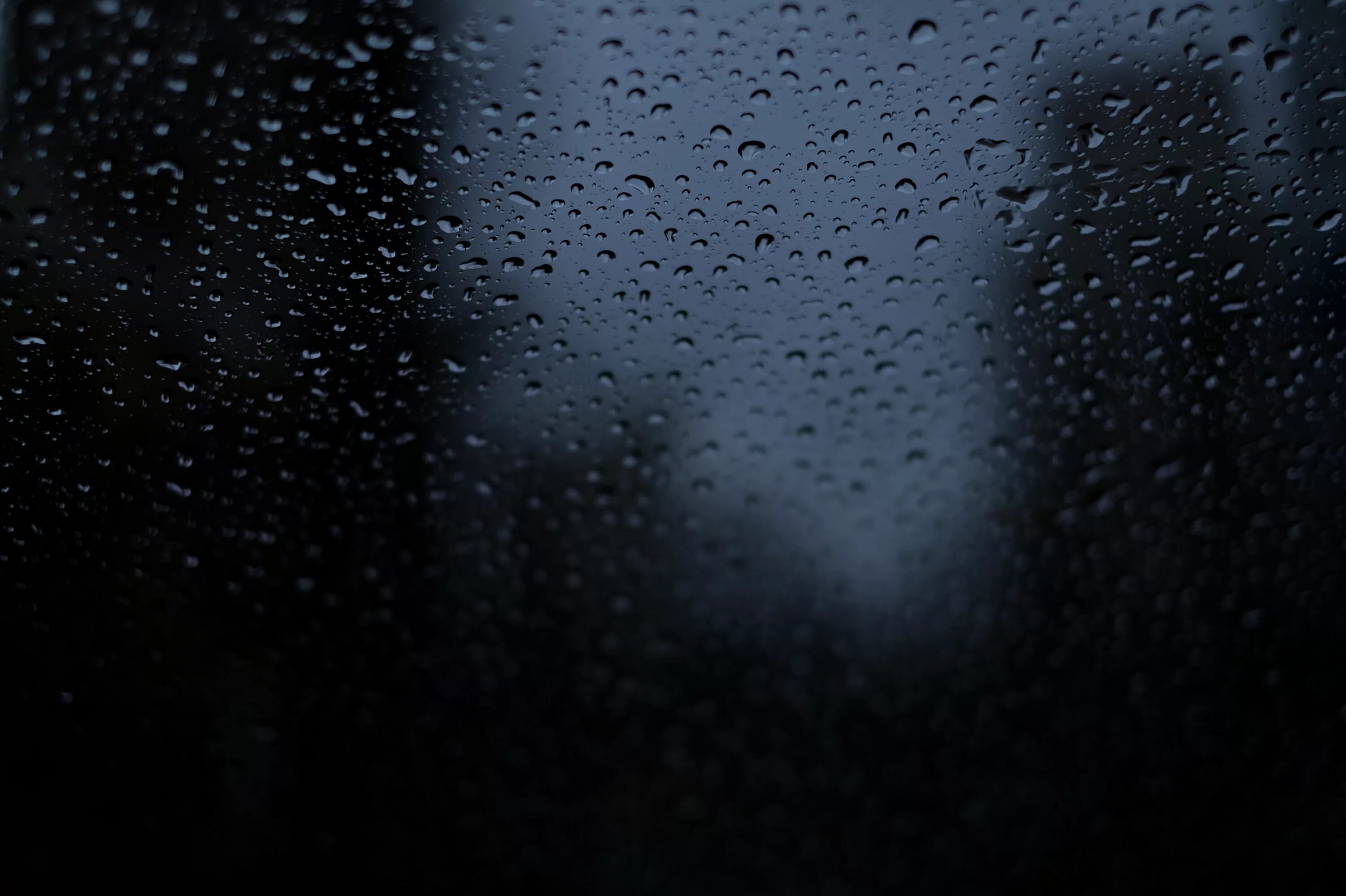 В темных каплях дождя. Капли на стекле. Текстура стекла. Дождь на черном фоне. Черное стекло фактура.
