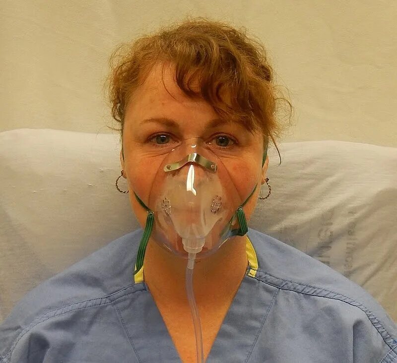 Кислородная маска надеть. Оксигенотерапия через кислородную маску. Человек в кислородной маске. Пациент с кислородной маской. Кислородная маска в больнице.