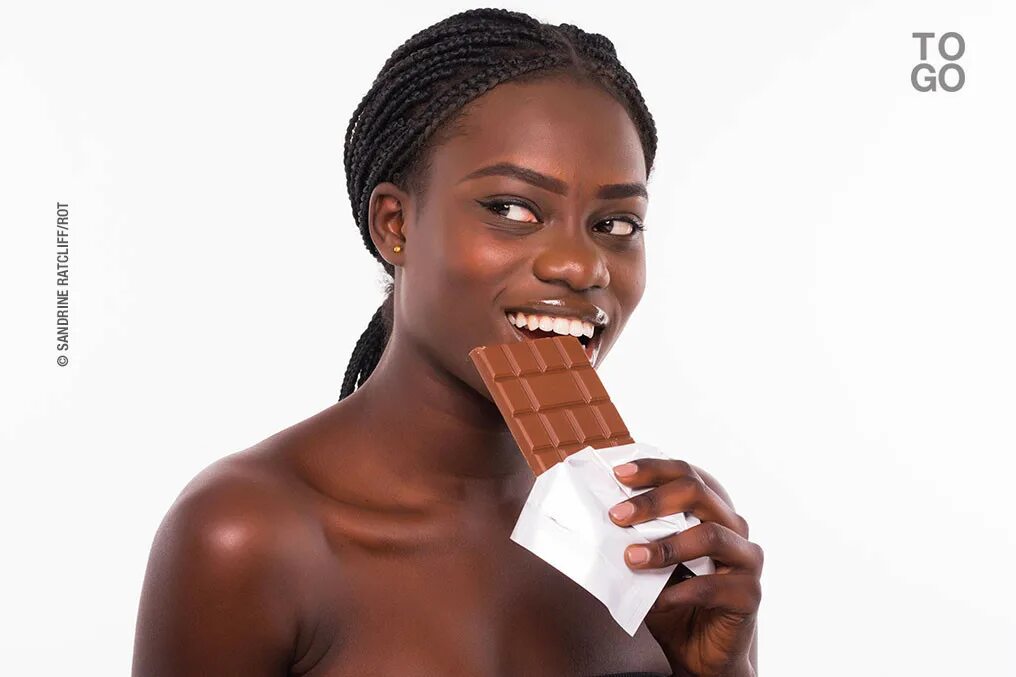 Темнокожий ест шоколад. Негритянка ест шоколад. Афроамериканец ест шоколад.