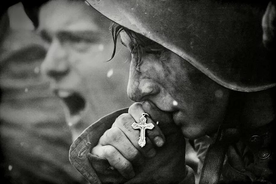 Солдат целует крест. Солдат молится.