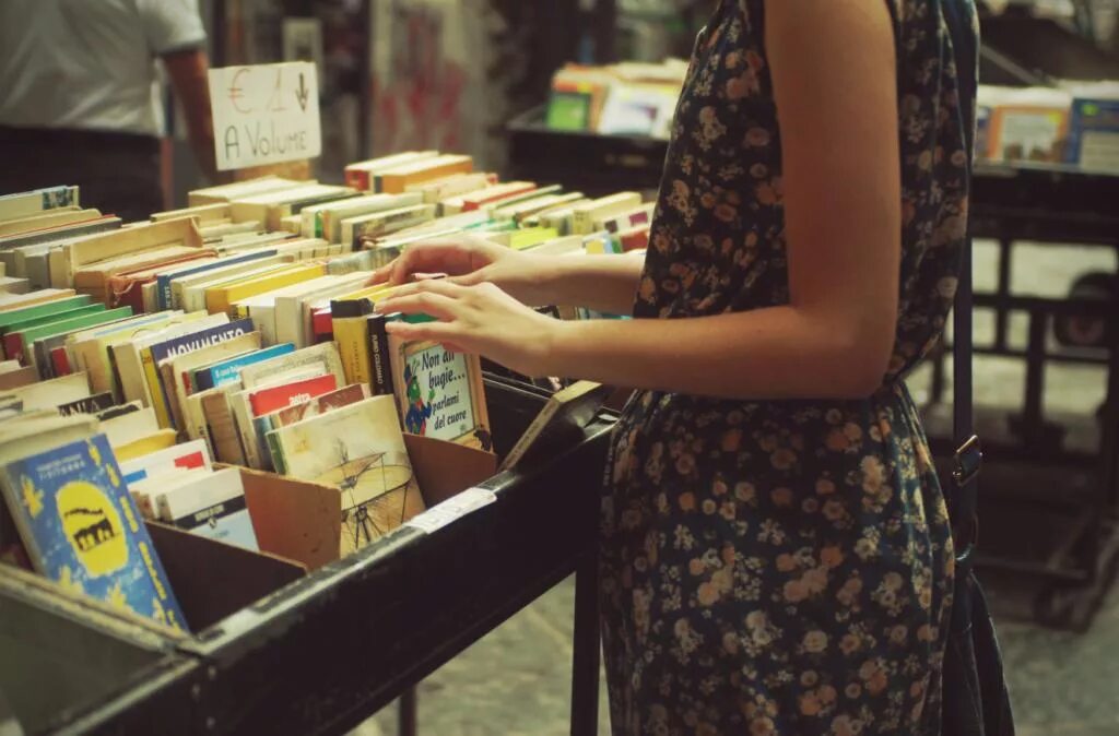 Книжный рынок. Покупатели в книжном магазине. Девушка выбирает книгу. Девушка который продает книги.