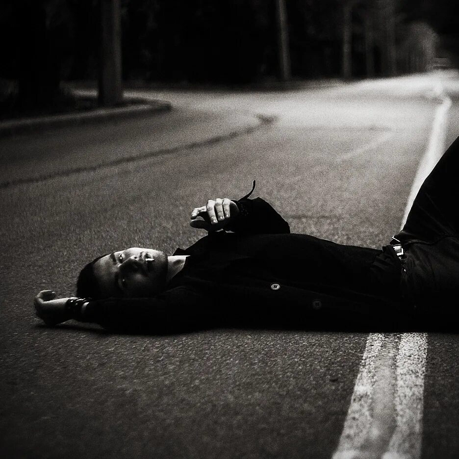 Парень лежит. Мужчина лежит на дороге ночью. Парень лежит на асфальте.
