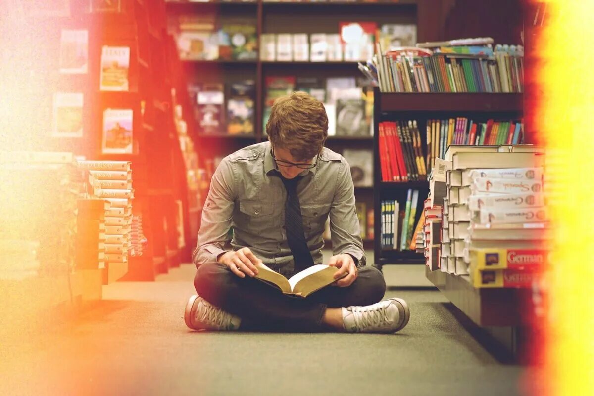 Чтение книг в библиотеке. Парень с книгой. Человек с книжкой. Парень в библиотеке. Парень с книгой в библиотеке.