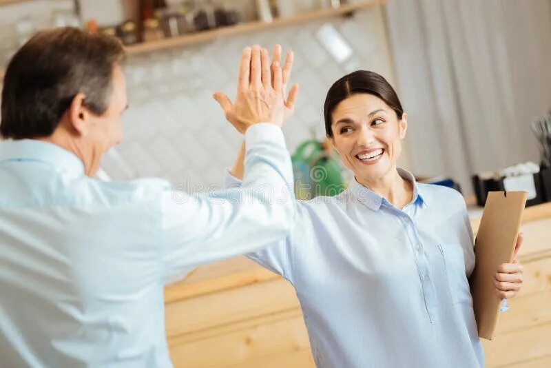 Удовлетворенный человек. Энергичное выступление. Give a High Five. People smiling to each other. Feeling of satisfaction