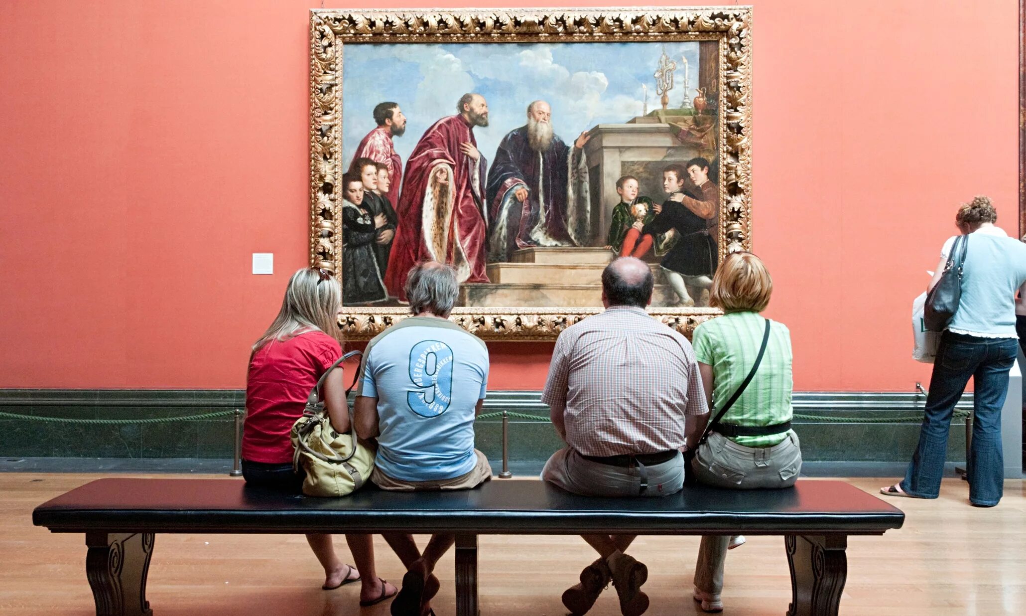 Люди рассматривают картины в музее. Люди в художественной галерее. Картина на стене в музее. Любование картиной.