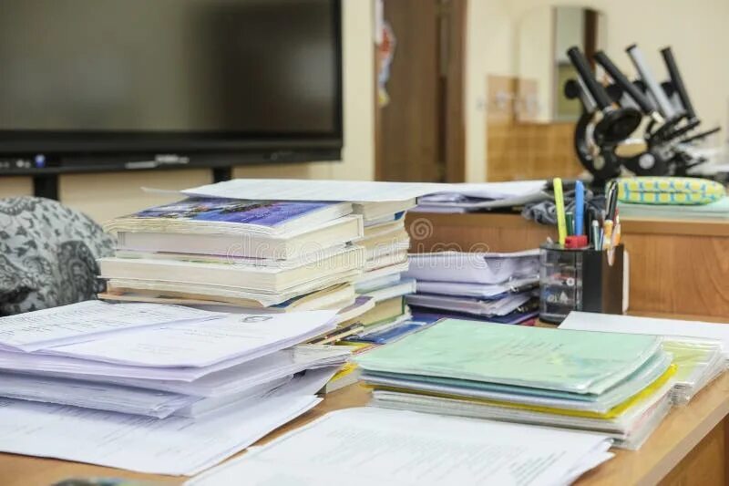 Стопка школьных тетрадей. Учительская тетрадь. Стол с учебниками и тетрадями. Много тетрадей. Тетради лежат стопки.
