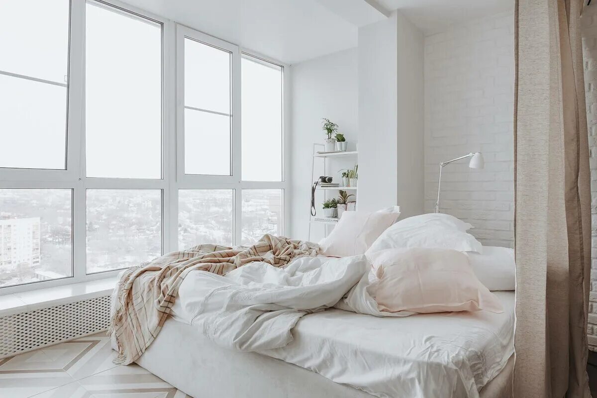 Кровать у окна в спальне. Белая спальня с панорамными окнами. Интерьер кровать у окна. Интерьер комнаты с окном.