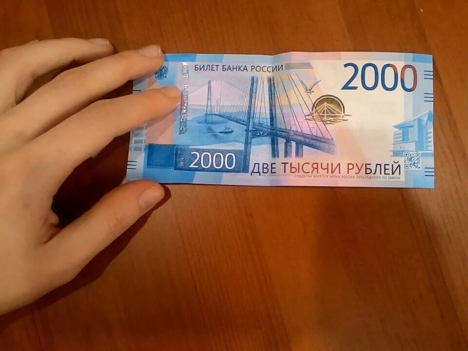 4000 тыс руб. 2000 Рублей банкнота. Две тысячи рублей в руках. Купюра 2000 рублей в руках. Купюра 2000 рублей на столе.