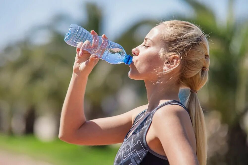 Питьевая вода на улице. Девушка пьет воду. Девушка пьет воду из бутылки. Питьевой режим. Жевушкк пьет из бутылки.