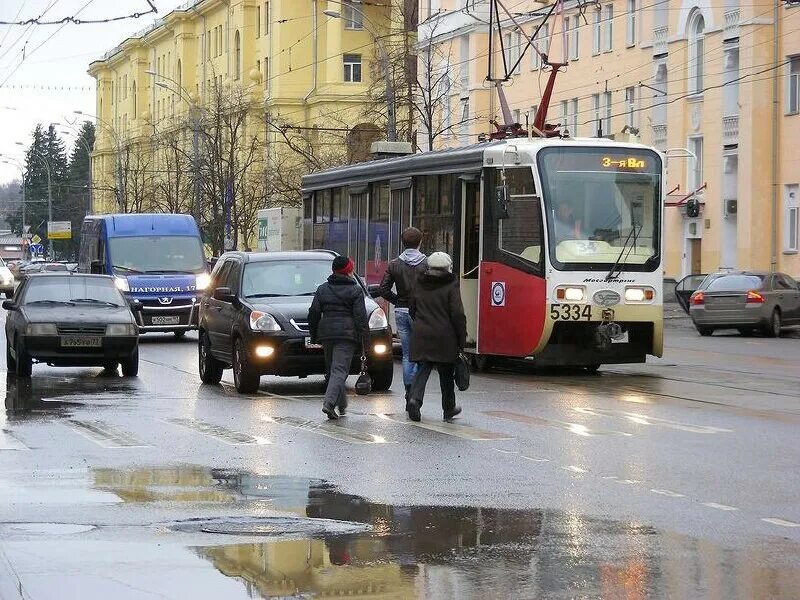 Улица с трамваем. Пассажиры на остановке. Высадка пассажиров трамвая. Водитель должен уступить дорогу пешеходам. Пешеход на трамвайных путях.