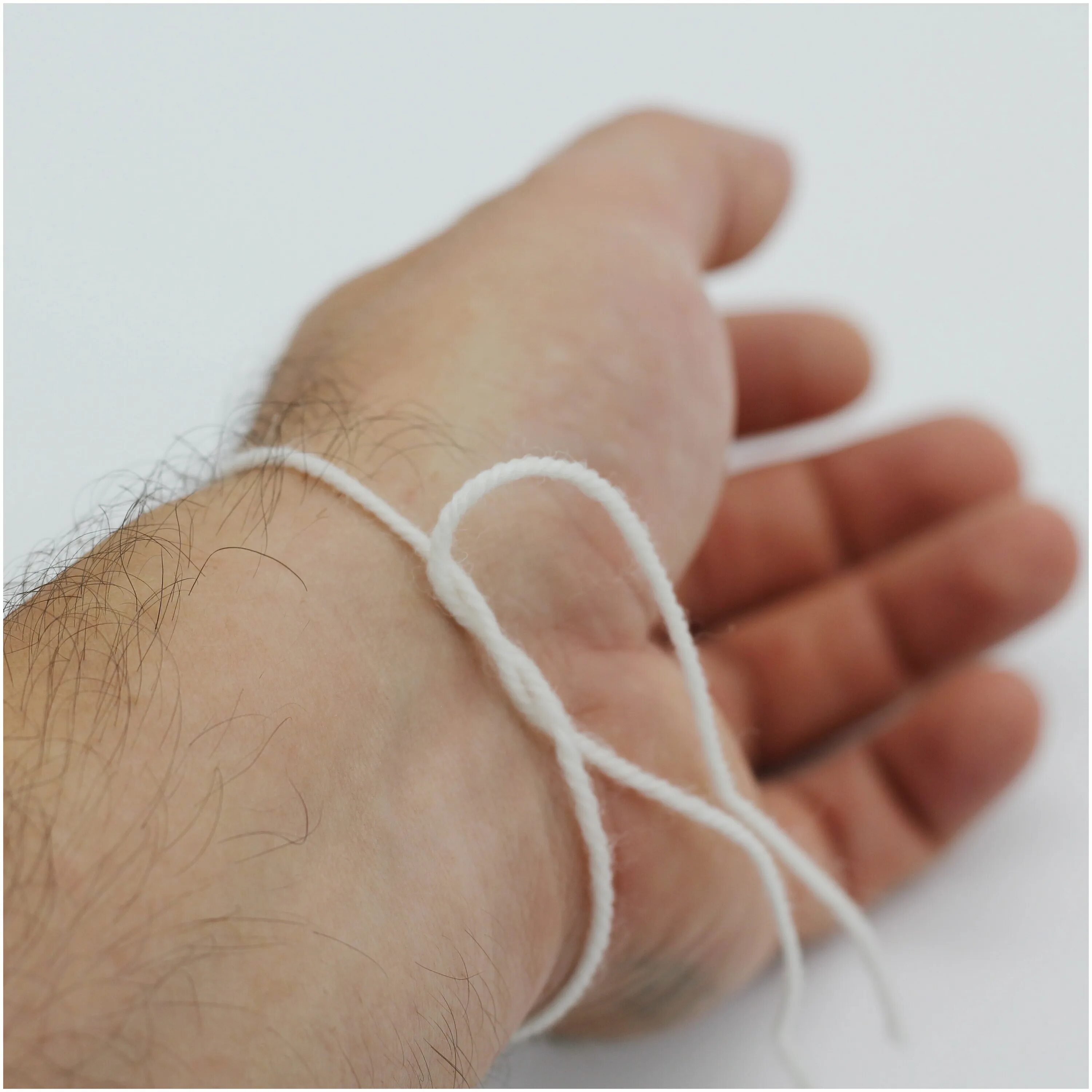 белый плетеный браслет. браслет белая нить. белый браслет из ниток. белая нитка на запястье. браслеты из белых нитей.