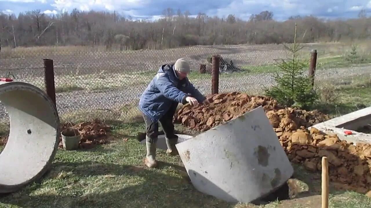 Опускание бетонных колец вручную. Механизм опускание бетонных колец. Опустить бетонное кольцо в яму без крана. Опускание колец ЖБИ без крана.